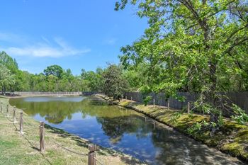 a pond with trees and a fence around it at Reserve of Jackson Apartment Homes, Jackson
